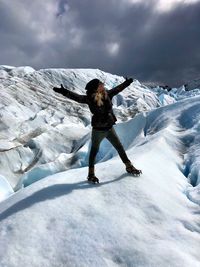 Woman with arms outstretched standing against snowcapped mountains 