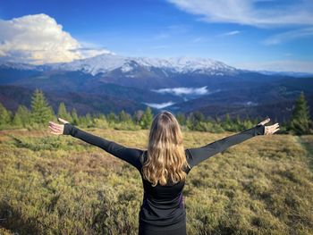 Selective focus of woman with her arms outstretched enjoying the beautiful snowcapped mountains