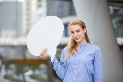 Portrait of young woman standing against built structure