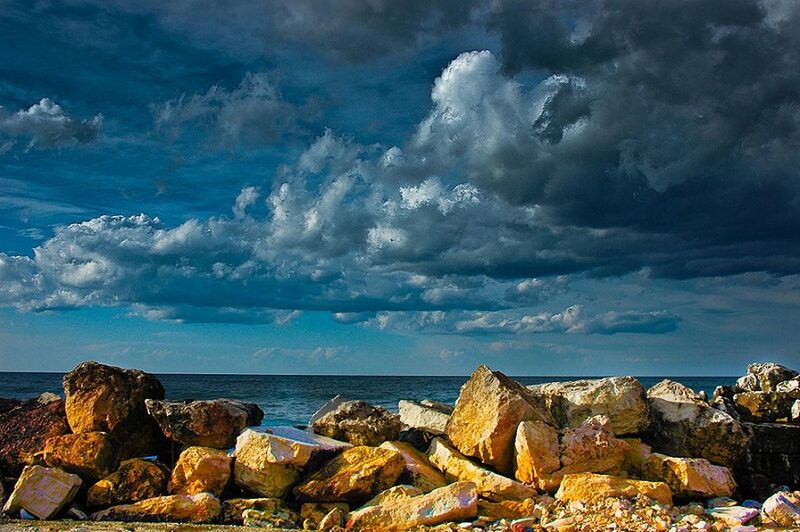 SCENIC VIEW OF SEA AND ROCKS AGAINST CLOUDY SKY