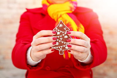 Midsection of woman holding gingerbread cookie during christmas