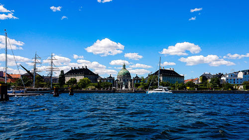 Panoramic view of buildings by river against blue sky
