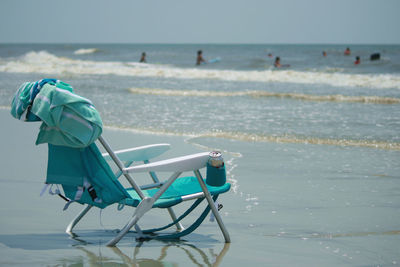 Close-up of deck chair on beach against sky
