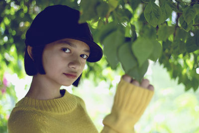 Close-up portrait of teenage girl standing under tree