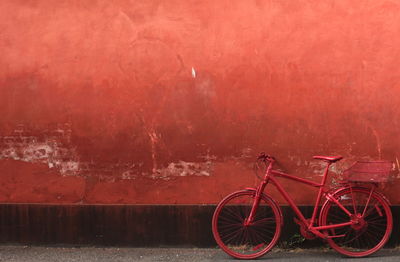 Bicycle parked against red wall