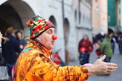 Man in clown costume performing on road in city