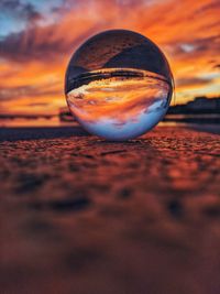 Close-up of crystal ball on beach during sunset