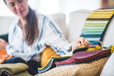 Working mother with daughter choosing fabric from swatch at home office