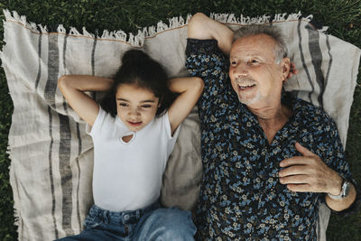 Directly above view of grandfather and granddaughter lying on picnic blanket