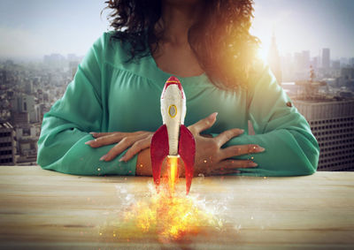 Full length of woman sitting on table in city against sky