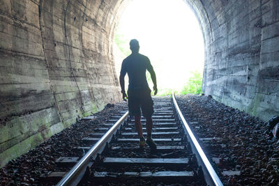 Rear view of man standing on railroad track