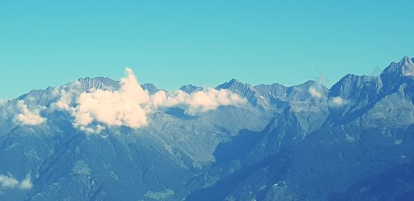 Panoramic view of snowcapped mountains against clear blue sky