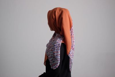 Side view of woman wearing hijab while standing against wall