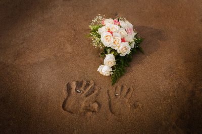 High angle view of rose bouquet and handprints at beach