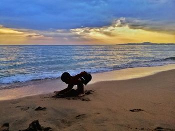 Full length of man on beach against sky during sunset