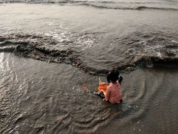 Rear view of man and woman sitting at sea