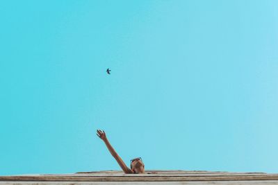 Low angle view of woman flying against blue sky