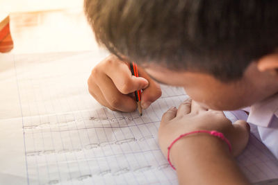 Close-up of boy writing on notebook