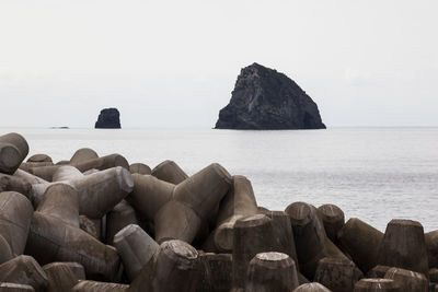 Tetrapod in sea against clear sky