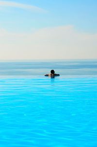 Man swimming in pool against sea