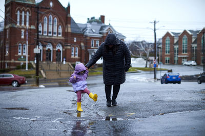 A mother and child playing in puddles on a rainy day.