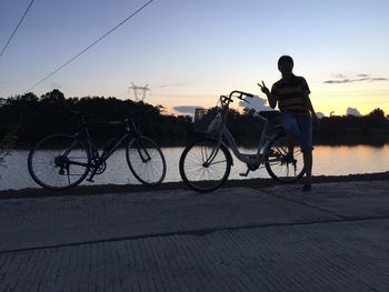 Silhouette man cycling on bicycle against sky