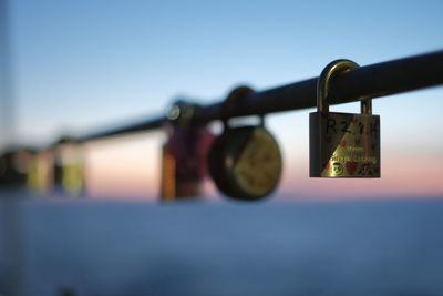 Close-up of padlocks on railing against sky