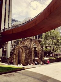 Bridge over road by buildings against sky