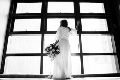 Rear view of woman standing against white window