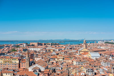 High angle view of townscape by sea against blue sky