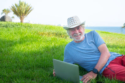 Portrait of smiling young man using mobile phone in field