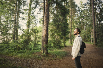 Full length of man standing amidst trees in forest