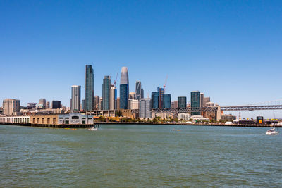 Sea by buildings against clear sky