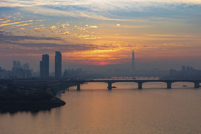 Bridge over river in city during sunset