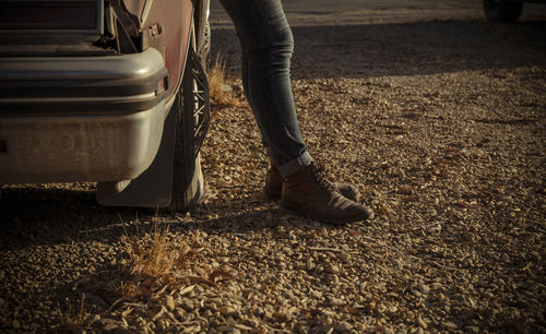 Closeup of headlights of an old, dirty car with legs of adult man