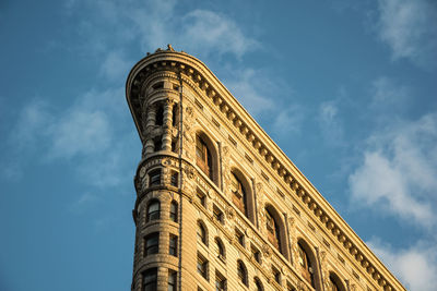 Low angle view of flatiron building against cloudy sky