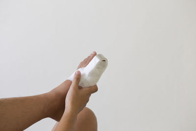 Cropped hand of woman holding paper against white background