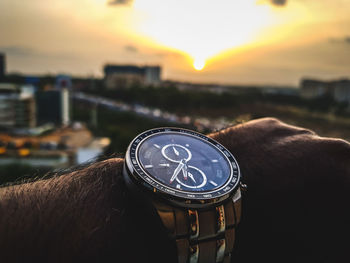 Close-up of human hand against the sky at sunset