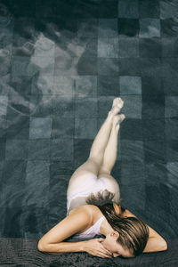 Young woman leaning on edge of swimming pool