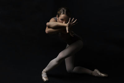 Portrait of ballet dancer exercising against black background