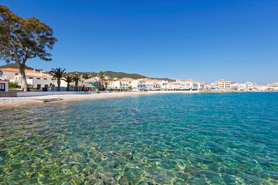 Scenic view of sea by buildings against clear blue sky