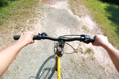 Cropped hands of woman riding bicycle on footpath
