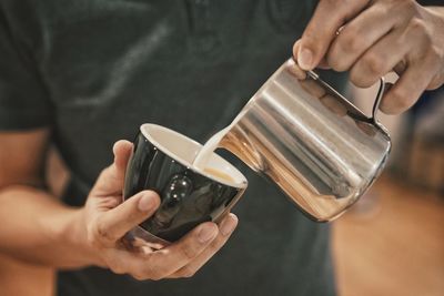 Midsection of man pouring coffee in cup