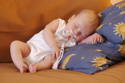 Full length of baby sleeping on sofa at home