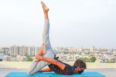 Full length of man relaxing on city against sky