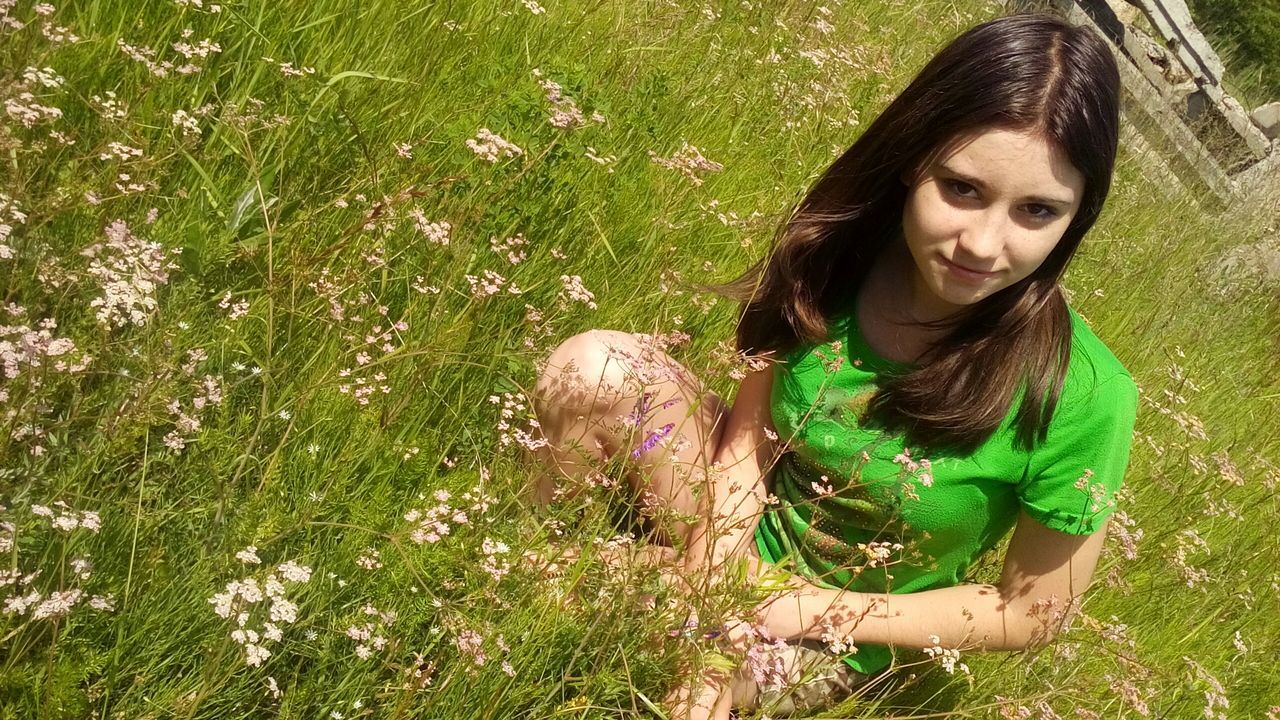 grass, person, young adult, lifestyles, looking at camera, young women, leisure activity, portrait, field, casual clothing, smiling, grassy, growth, green color, standing, flower, three quarter length, park - man made space