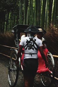 Rear view of man standing against rickshaw in bamboo groove