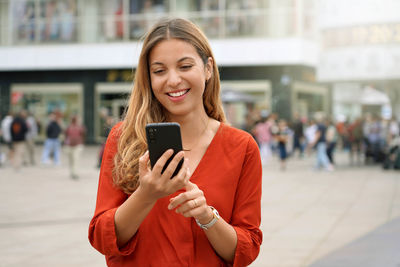 Portrait of smiling young woman using a smartphone app in berlin, germany
