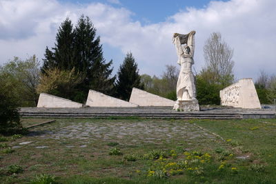 Statue by tree against sky