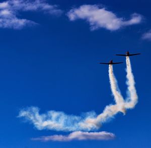 Low angle view of airplane flying against blue sky